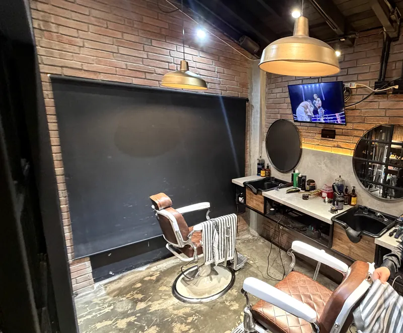 Estación de barbero: ladrillo a la vista, lámpara de latón y sillas de cuero cognac